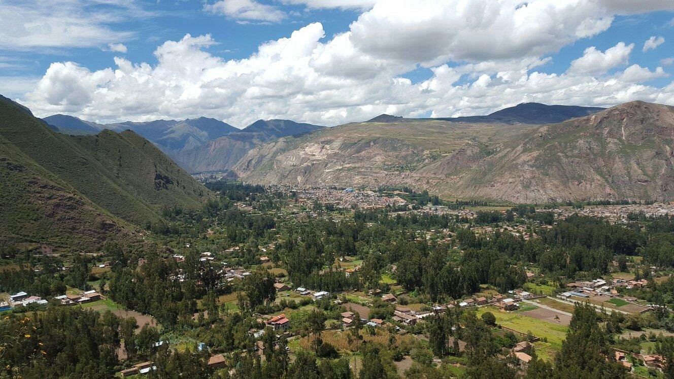 La Capilla Lodge’s valley, a town among green trees below mountains and white clouds